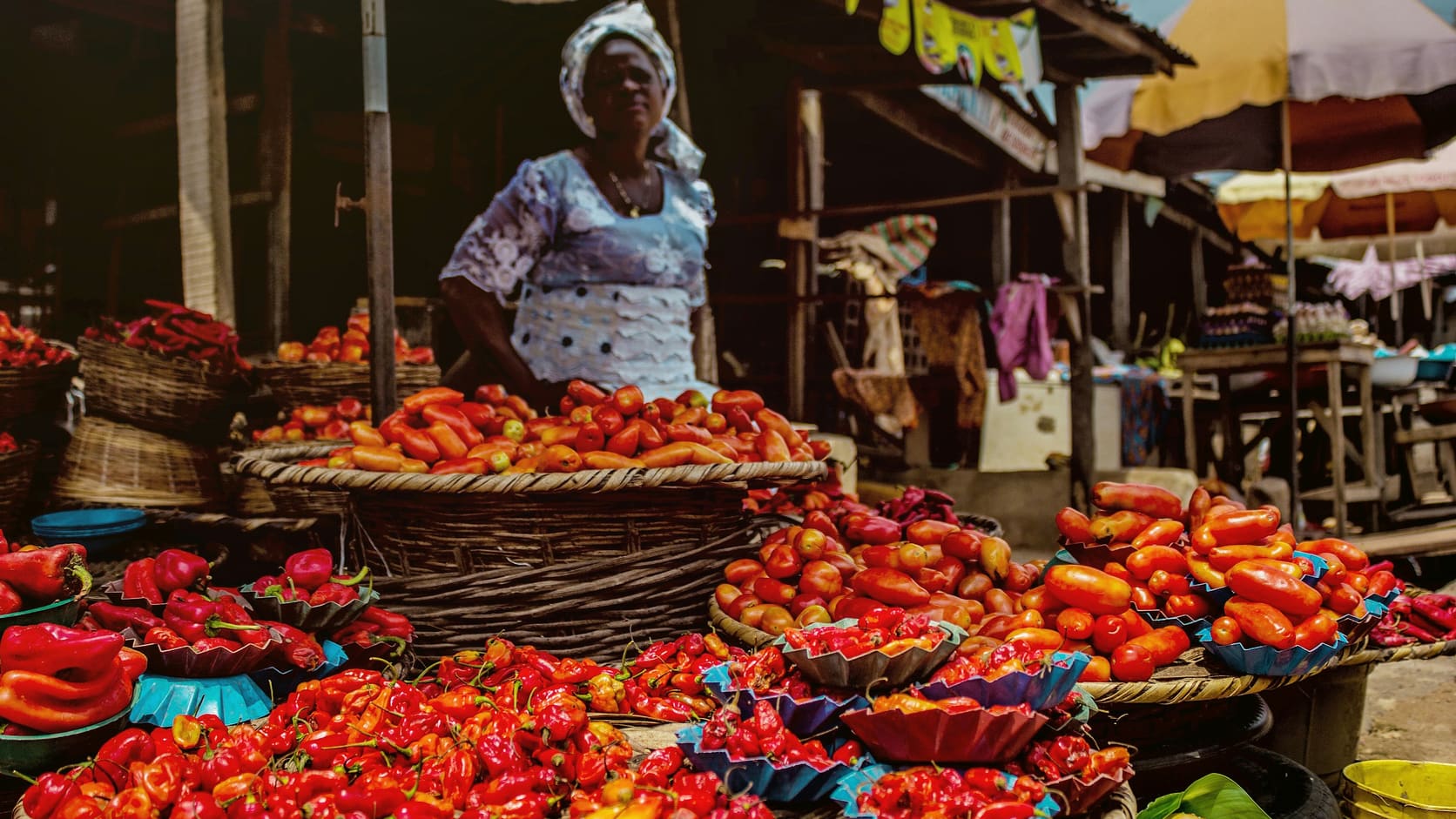 Illustrative open-air market stall with baskets of fresh produce and a vendor