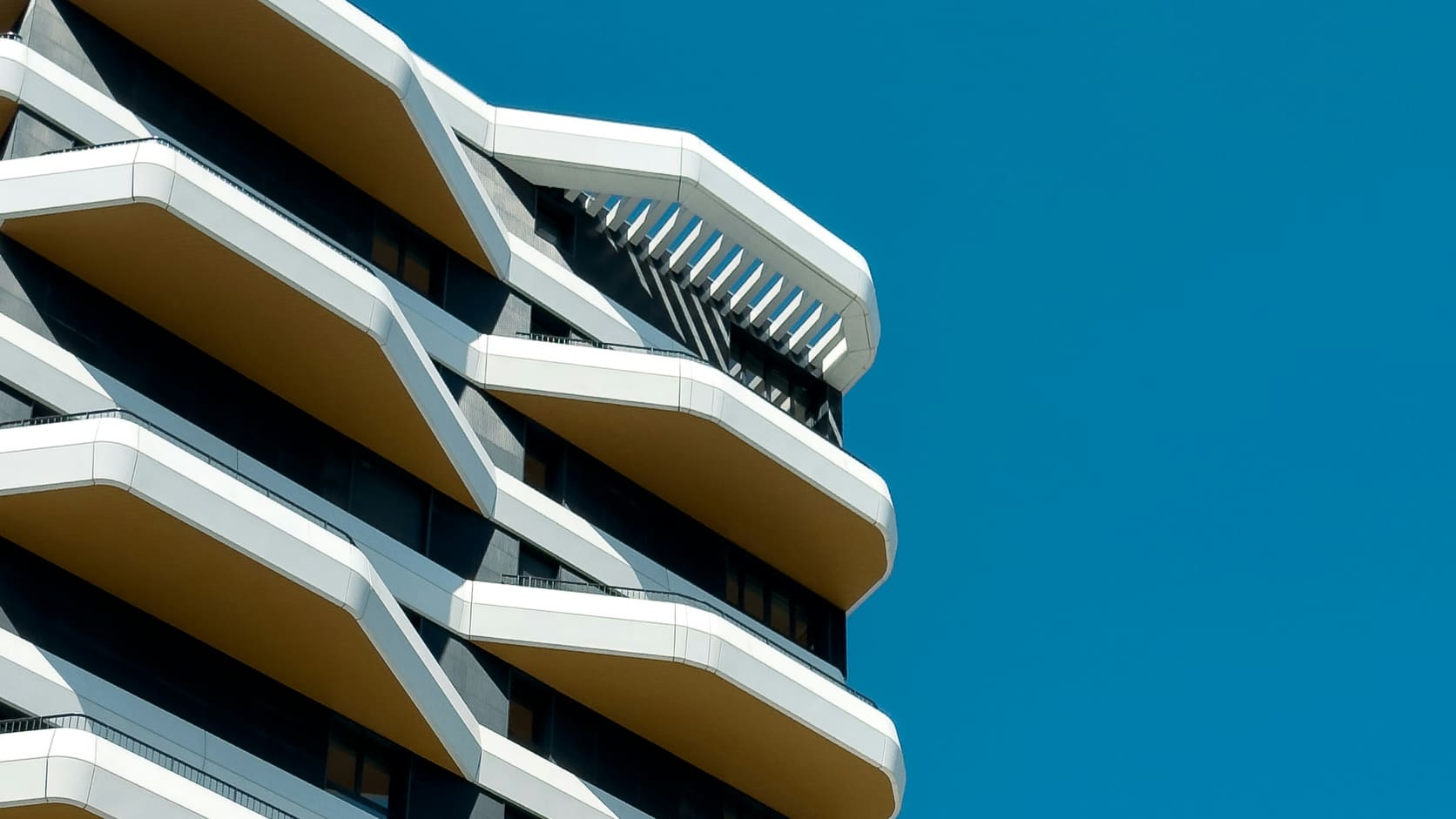 Illustrative modern apartment building facade with sculptural white balconies against a clear blue sky